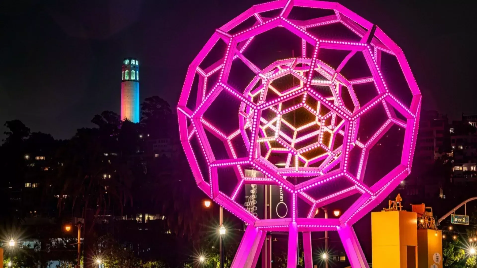 Buckyball brilla fuera del Exploratorium, con la Torre Coit al fondo